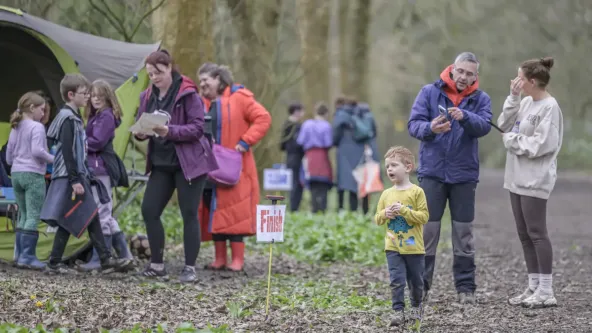 A group of orienteers can be seen near a tent, the two groups contain adults and children at a finish line